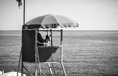 Rear view of man sitting on sea against sky