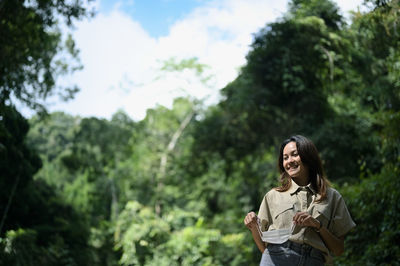 Young woman remove surgical mask from her face , surrounded by fresh environment of green forest