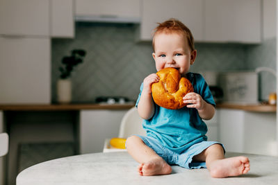 Cute boy eating bread at home