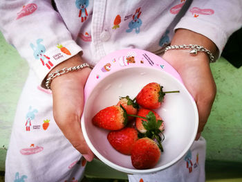 High angle view of woman with strawberries in plate