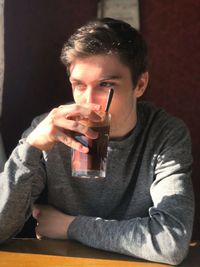 Young man having drink at table in cafe