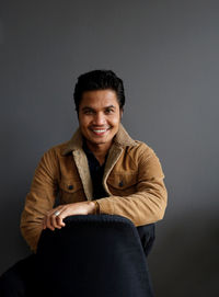Portrait of smiling young man sitting against wall