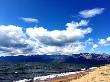 Scenic view of sea and mountains against blue sky