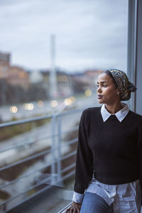 Young woman looking through window