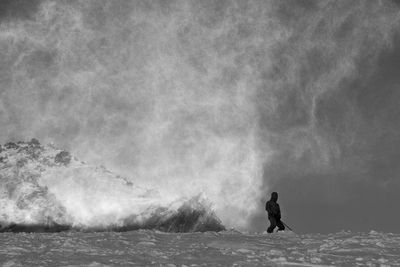 Person skiing on snow covered field against sky