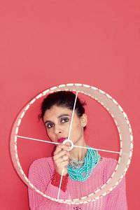 Portrait of woman holding equipment against wall