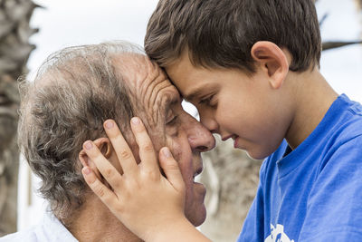 Side view of smiling boy holding grandfather
