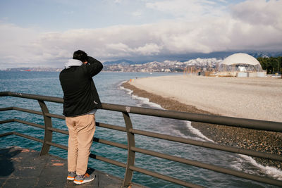 21.03.2022. batumi, georgia. a man takes a photo of the sea coast of the city from the pier. 