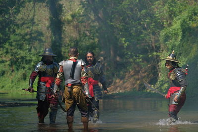 Male warriors discussing on lake at forest