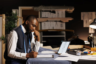 Side view of man using laptop while sitting in office