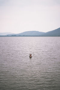 Man swimming in sea against sky