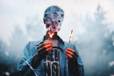 Portrait of man holding fire against blurred background