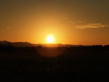 Scenic view of silhouette field against sky during sunset