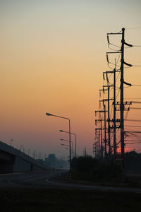 Silhouette street light against orange sky