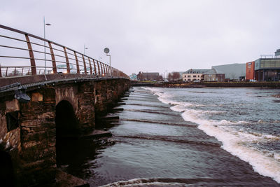 Bridge over sea against sky in city