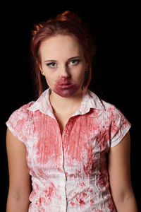 Close-up portrait of young woman in halloween costume over black background