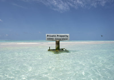 Information sign by swimming pool against sky