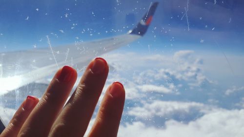 Close-up of human hand against sky