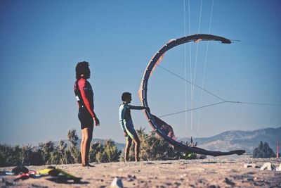 Full length of friends on land against clear blue sky