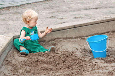 Child baby in sandbox playing with beach toys. girl toddler watching exploring sand on hands. 