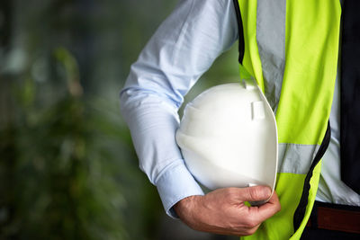 Midsection of man holding hardhat