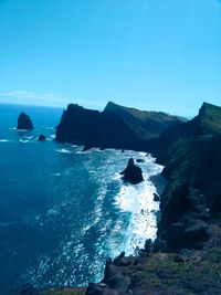 Rock formations in sea against clear blue sky