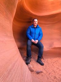 Full length portrait of man sitting at canyon