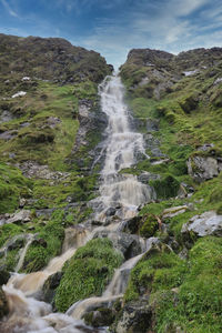 Scenic view of waterfall against sky