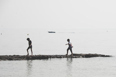 Men standing on beach against clear sky