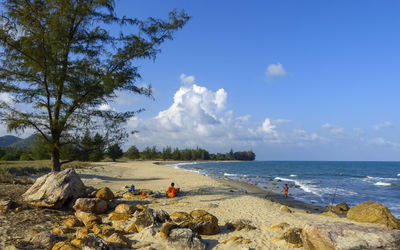 Boy fishing in sea with man against sky