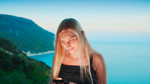 Young woman looking at sea against sky