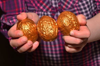 Midsection of child holding walnut shape golden toys