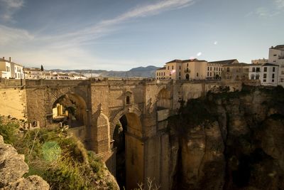 Arch bridge over buildings against sky