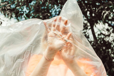 Midsection of woman holding umbrella against trees