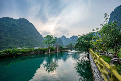 Scenic view of river by mountains against sky