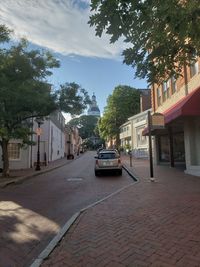 Cars on street by buildings in city against sky