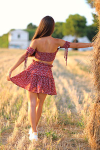 Rear view of woman with arms raised on field