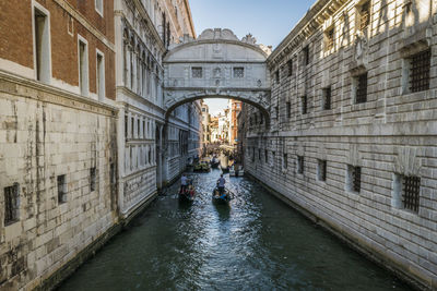 High angle view of people on gondolas sailing canal amidst buildings in town