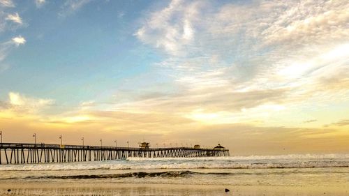 Pier over sea against sky during sunset