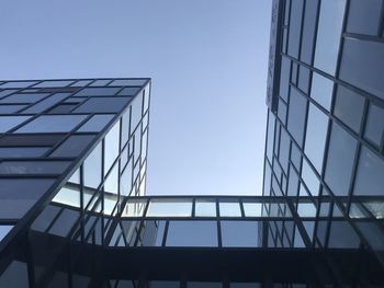 Low angle view of glass building against clear blue sky