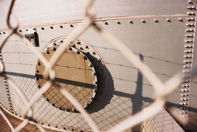 Metal container in factory seen through chainlink fence