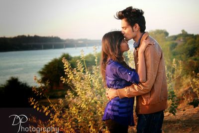 Young man kissing woman on forehead while embracing