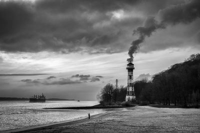 View of tower on beach against cloudy sky
