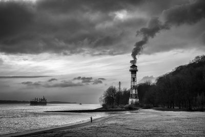 View of tower on beach against cloudy sky