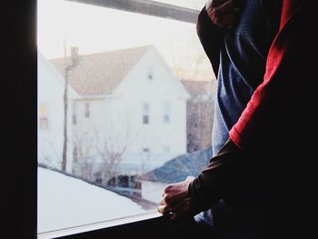Midsection of man holding glass window at home