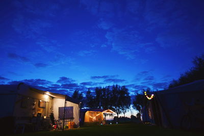 Illuminated buildings against blue sky at night