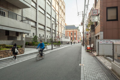 People walking on street amidst buildings in city