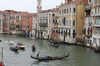 Boat, gondola with tourists and a gondolier that steers the boat,  old venetian buildings	