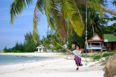 People walking on beach against palm trees