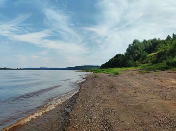 The coastline of the river against the background of a beautiful blue sky with clouds